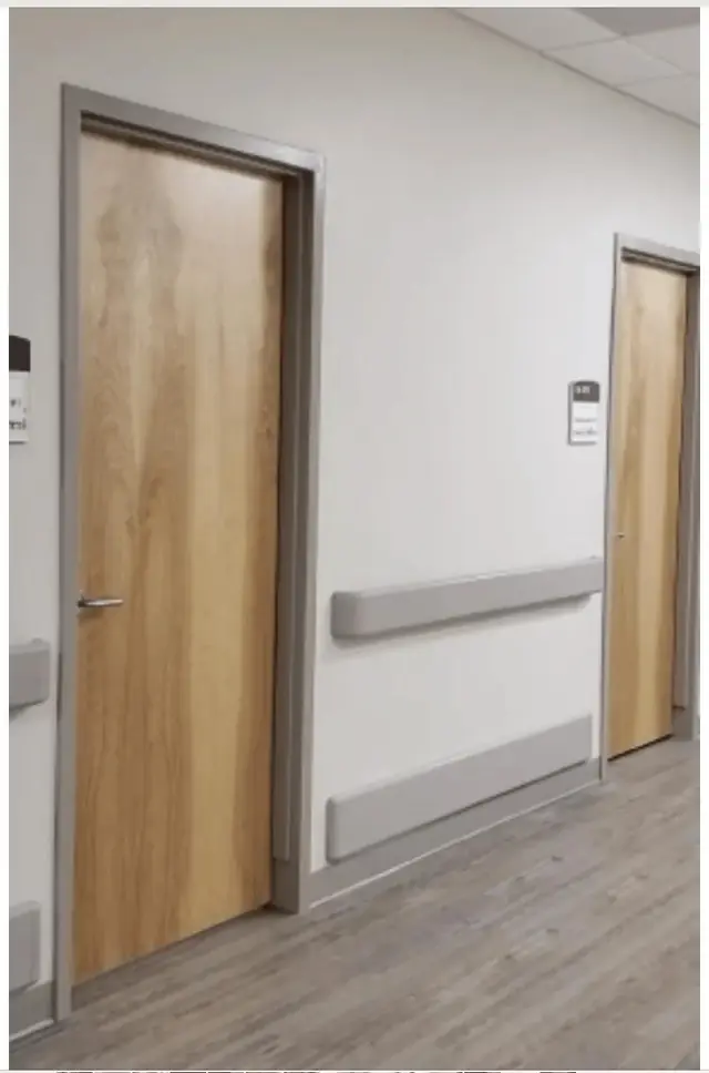 Wood veneer doors in grey metal frames along a healthcare corridor