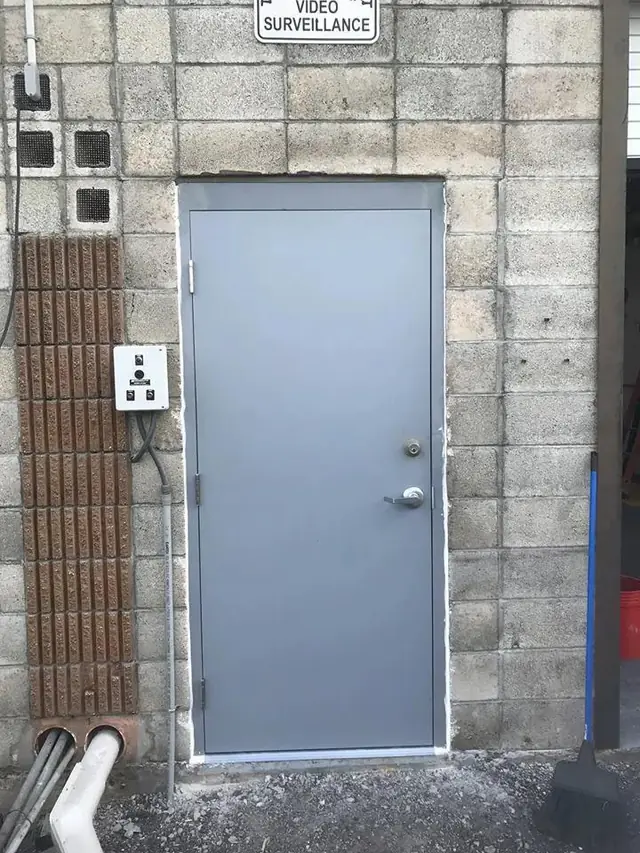 Grey hollow metal door installed in a concrete block wall