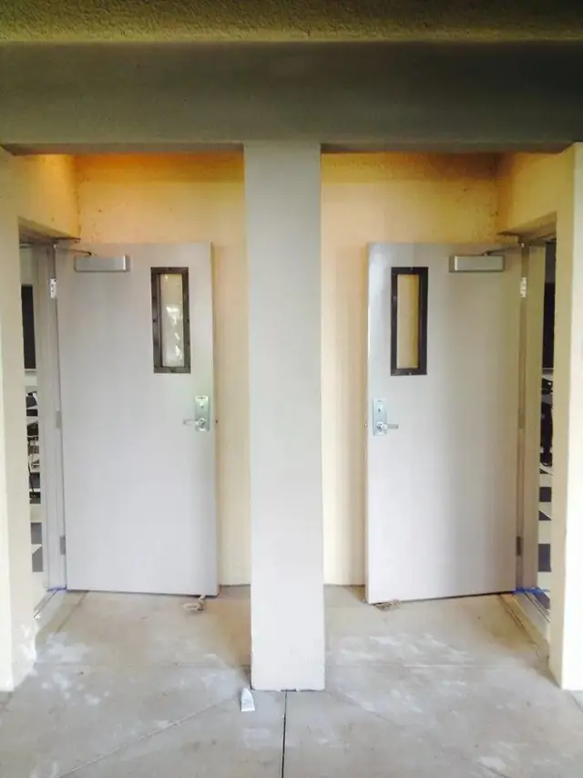 Pair of metal doors with vision lites and closers in a breezeway